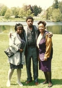 A man and two women posed in front of a lake.