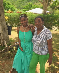 Two smiling women stand outside with trees and colorful foliage in the background. 