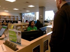 A student worker sitting at the library welcome desk.