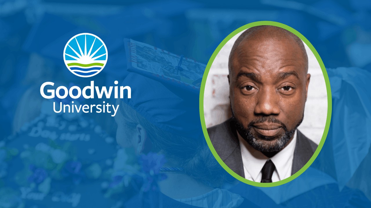 Portrait of a man in a suit against a blurred graduation scene with the Goodwin University logo