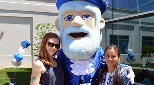 Two students posing with the Navigator mascot