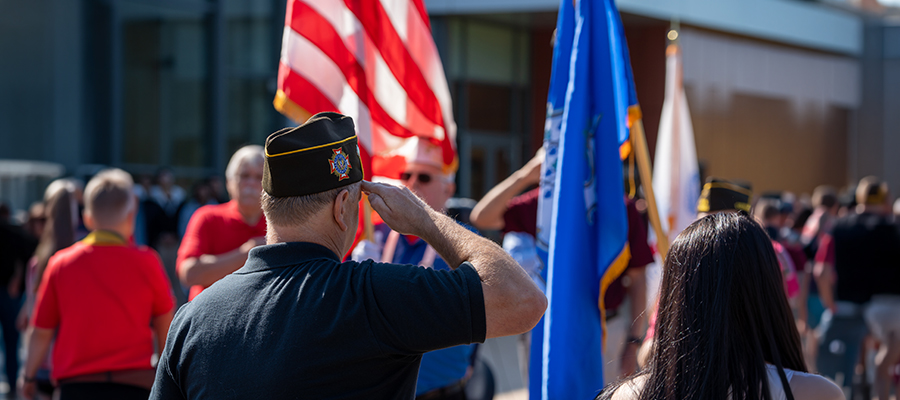 A male veteran salutes the U.S. flag.