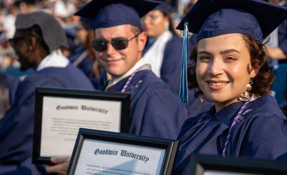 two students holding up their diplomas at Commencement