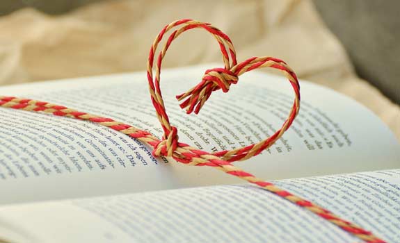 string in the shape of a heart over an open book