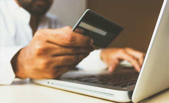 person holding a credit card while typing on a laptop
