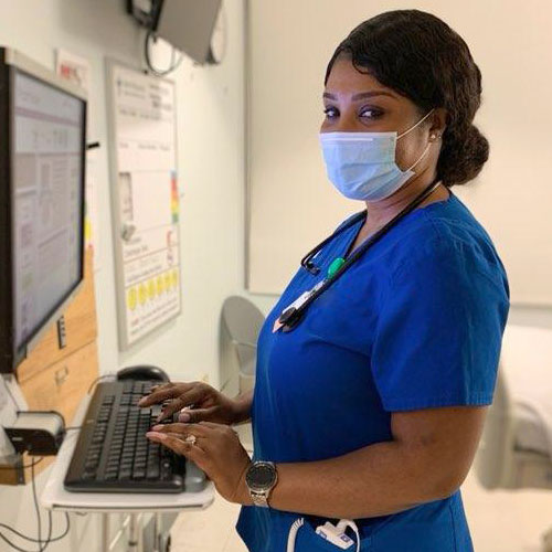 Belinda in nursing scrubs at a computer