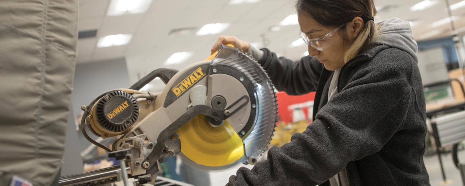 ECAMP student using a compound miter saw