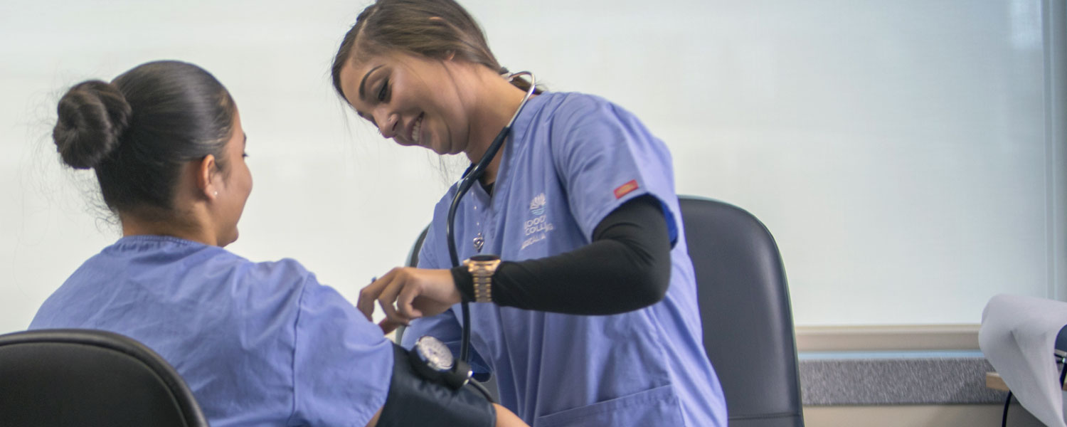 Medical Assisting student practicing using a blood pressure cuff