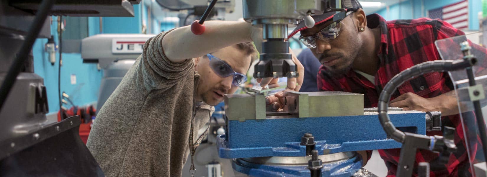 two students setting up manufacturing equipment