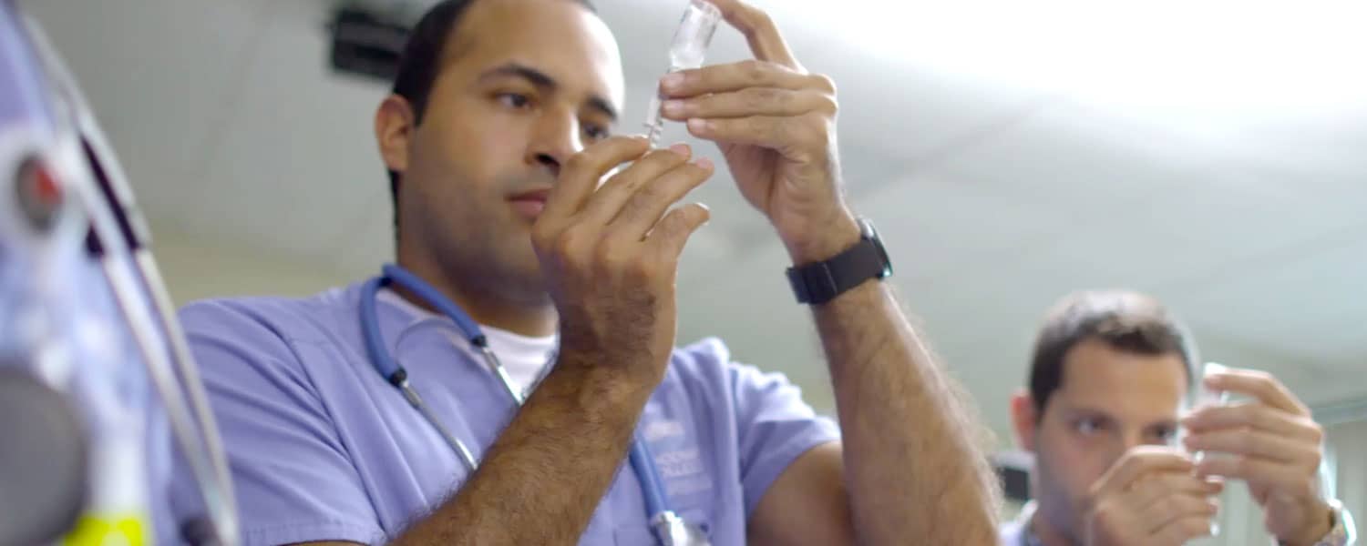 Nursing students checking fluid in syringes