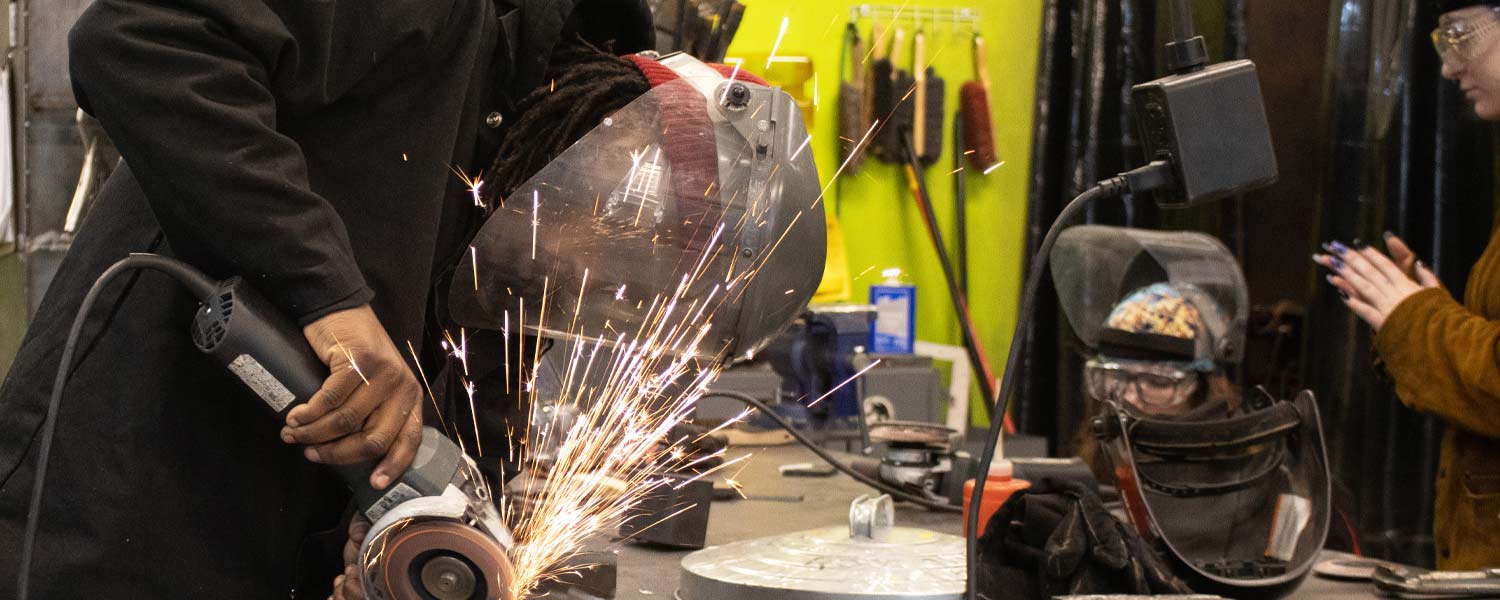 Welding student using an angle grinder